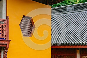 Hexagonal window on yellow wall with black roof in Lingyin Temple, Hangzhou, China