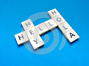 Hey Hola Hello made of square letter tiles against blue background.