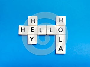 Hey Hola Hello made of square letter tiles against blue background.