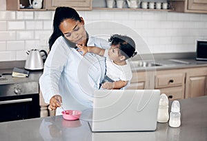 Hey, Im hungry. a young mother feeding her baby while using a laptop at home.