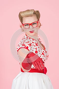 Hey you buddy! Shocked young blonde woman pointing by hand in red gloves at camera and open mouth. Studio shot of female model iso