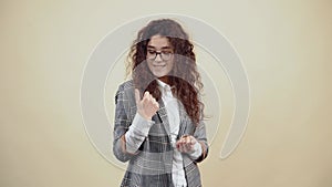 Hey you, come to me. Beautiful young woman with curly hair in a gray jacket and white shirt, with glasses posing