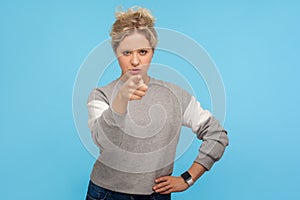 Hey you! Displeased bossy woman with short curly hair in sweatshirt pointing finger to camera and blaming