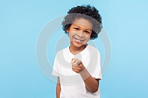 Hey you! Portrait of cheerful funny little boy with curly hair pointing finger to camera and smiling, child making choice