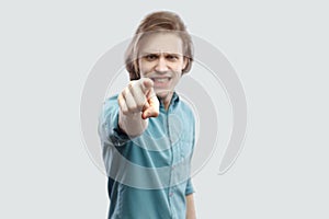 Hey you. Portrait of serious blame handsome long haired blonde young man in blue casual shirt standing, pointing, alarming and photo