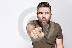 Hey You! Portrait of surprised excited bearded man with dark green t shirt against light gray background.