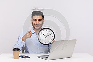 Hey you, watch time! Positive punctual man employee with angelic nimbus sitting in office workplace