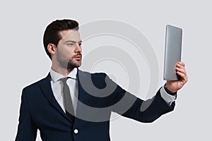 Hi! Good looking young man in full suit holding digital tablet a