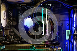 Hi-performance custom computer desktop with cooling pump installed on CPU processor and multicolored LED neon light show on workin