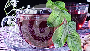 Hibiscus red tea mug with tea leaf or mint leaf close-up horizontal photo.Medicinal therapy on medicinal herbs and decoctions.