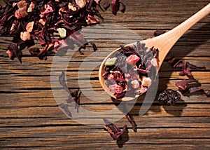 Hibiscus tea. Dry mix of red herbal and fruit tea over wooden surface