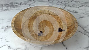 Hibiscus tea falling into wooden bowl. Marble worktop background