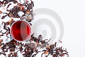 Hibiscus tea and scattered dried hibiscus on white background, top view