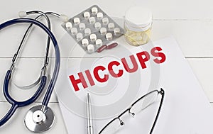 HICCUPS word on paper with stethoscope and pills