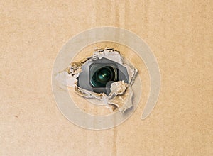 Hidden camera in torn hole in cardboard paper photo
