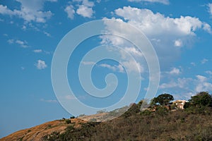 Hidden house on the top of a hill against a deep blue sky