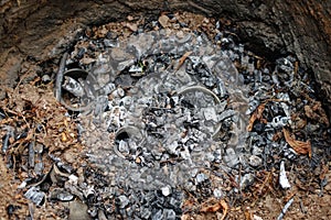 Hidden pottery pieces under ashes of wood in primitive pit fire kiln after burning