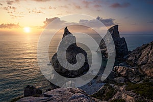 Hidden Praia Da Ursa - Ursa Beach, Sintra, Portugal. Two huge rocks rasing in evening golden sunset light at Atlantic