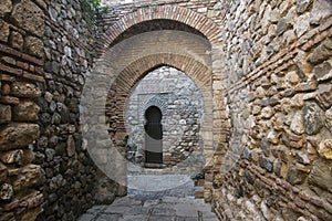 Hidden stone passageway in Malaga fortress with archs and gate photo