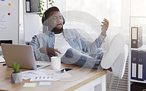 Cheerful employee playing virtual guitar while listening music at workplace