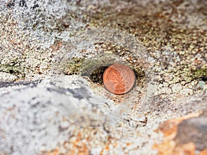 Hidden two euro cent coin in hole of sandstone