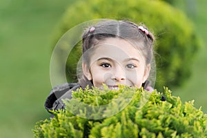 Hide and seek fun. Girl cute smiling kid green grass background. Healthy emotional happy kid relaxing outdoors. What