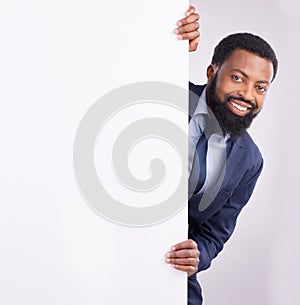 Hiding, portrait and a black man standing by a wall isolated on a white background in a studio. Mockup, happy and an