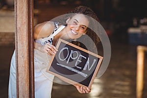 Hiding waitress showing chalkboard with open sign