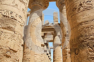 Hieroglyphs and ancient symbols on the columns of the Temple of Karnak, row of pillars in perspective