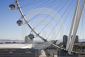 High above the city, a large observation wheel with modern capsules offers panoramic views under a clear blue sky