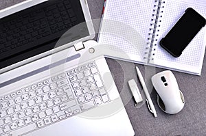 High above view of office workplace with mobile phone and laptop close up computer keyboard and mouse with notebook, pen and usb