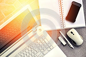 High above view of office workplace with mobile phone and laptop close up computer keyboard and mouse with notebook, pen and usb