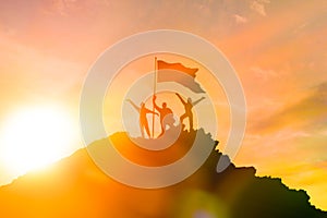 High achiever, silhouettes of three people holding on top of a mountain to raise their hands up.