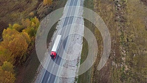 High Aerial view of alone red truck driving an interstate highway with trailer.