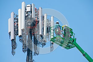 High in the air, workmen maintain a cell tower