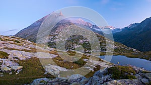 High altitude alpine lake in idyllic land with majestic rocky mountain peaks. Long exposure at dusk. Wide angle view on the Alps.