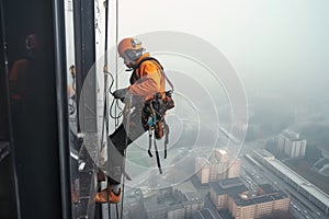 High-altitude climber. The profession of working at height. An industrial climber works on a skyscraper is attached by