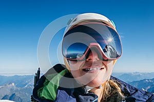 High altitude mountaineer smiling female portrait in safe ski helmet and goggles on the Mont Blanc 4810m with picturesque Alpine