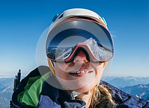High altitude mountaineer smiling female portrait in safe ski helmet and goggles on the Mont Blanc 4810m with picturesque Alpine