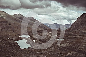 High altitude rocky landscape and little lake. Majestic alpine landscape with dramatic stormy sky. Wide angle view from above, ton