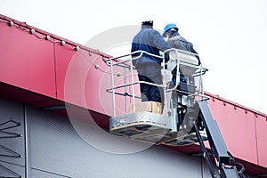 High-altitude works. Professional installation work on a construction building site. Assemblers perform high-altitude installation