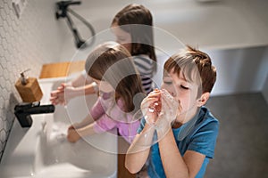 High anbgle view of little children in bathroom, washing hands and doing bubbles from soap.