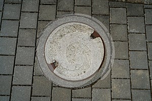 High angel shot of metal sewer manhole on a cobblestone street