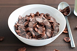 High angel view of chocolate cereal in a white bowl on brown background