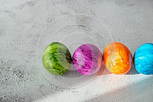 High angel view of multicolored colorful Easter eggs in sunbeam over gray textured background with copy space.