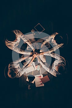 High angle above view vertical photo of four business partners sitting table working together late night holding arms