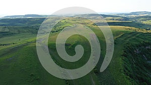 High angle aerial above view of green meadow in the spring, countryside hills