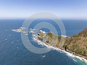 High angle aerial drone view of Nugget Point with its distinctive lighthouse, pathway leading to it and offshore rocks.