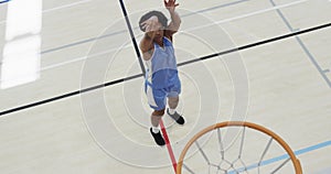 High angle of african american male basketball player shooting ball at hoop on court, slow motion