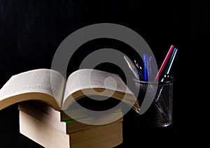 High angle close up shot of pen stand with books against black background